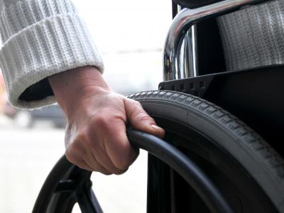 Imagem mostra uma pessoa guiando uma cadeira de rodas 