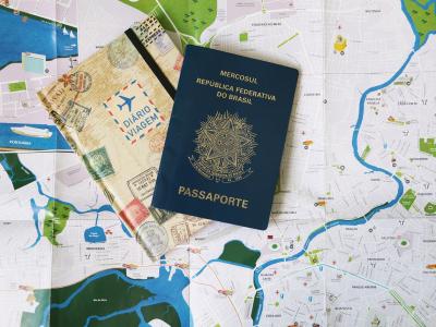 Imagem mostra um mapa, um caderno e um passaporte