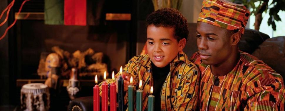 homem e criança negros olhando para velas e frutas em cima de uma mesa 